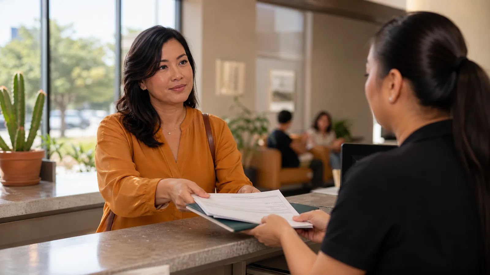 Woman handing her utility bill across a bright community office counter to a caseworker